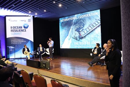 ITOPF on stage at Ocean Resilience Summit delivering presentation, ITOPF representative is standing with microphone in hand and blue shirt
